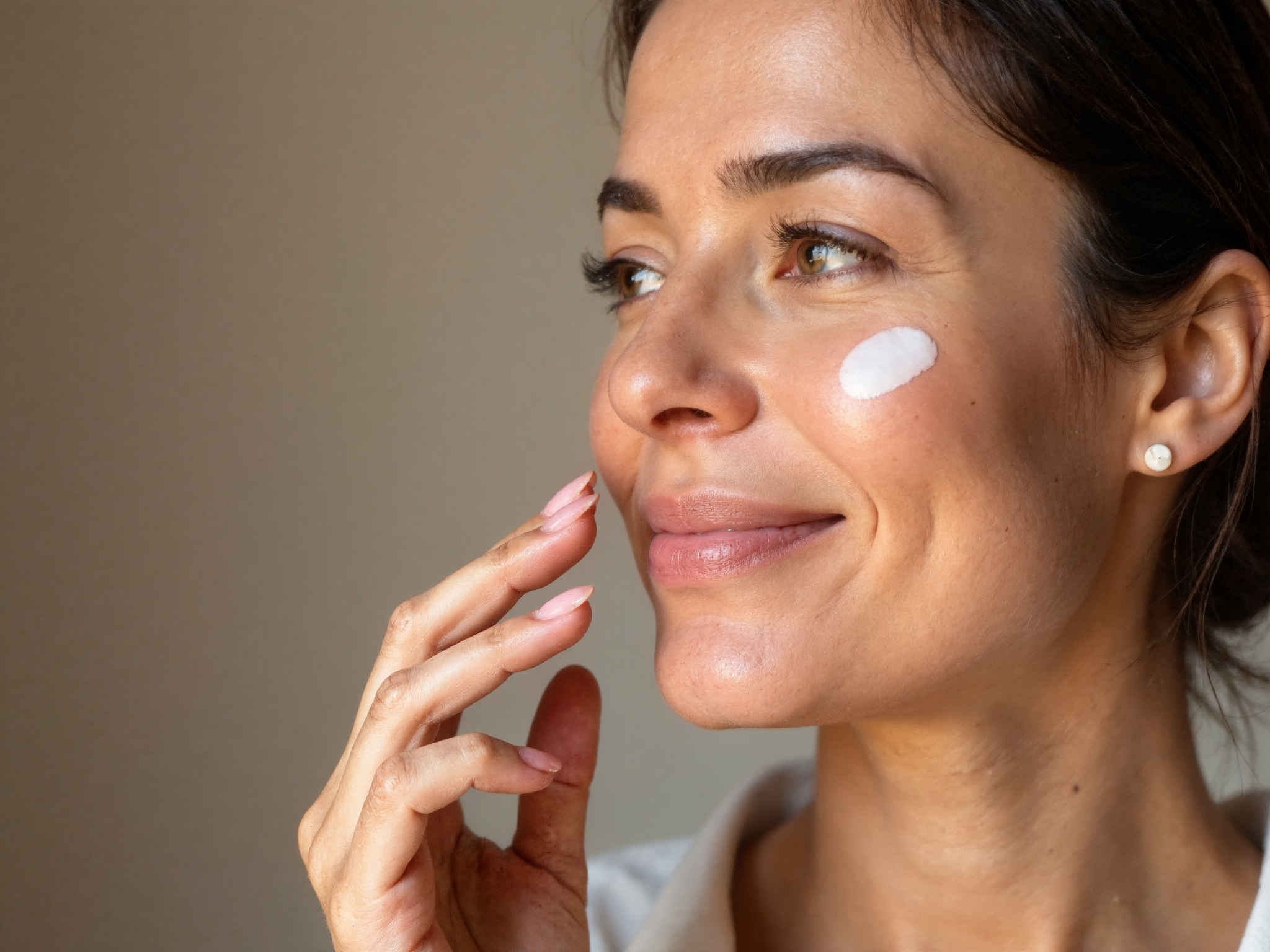 Woman testing skin elasticity by pressing finger into cheek to demonstrate bounce and firmness