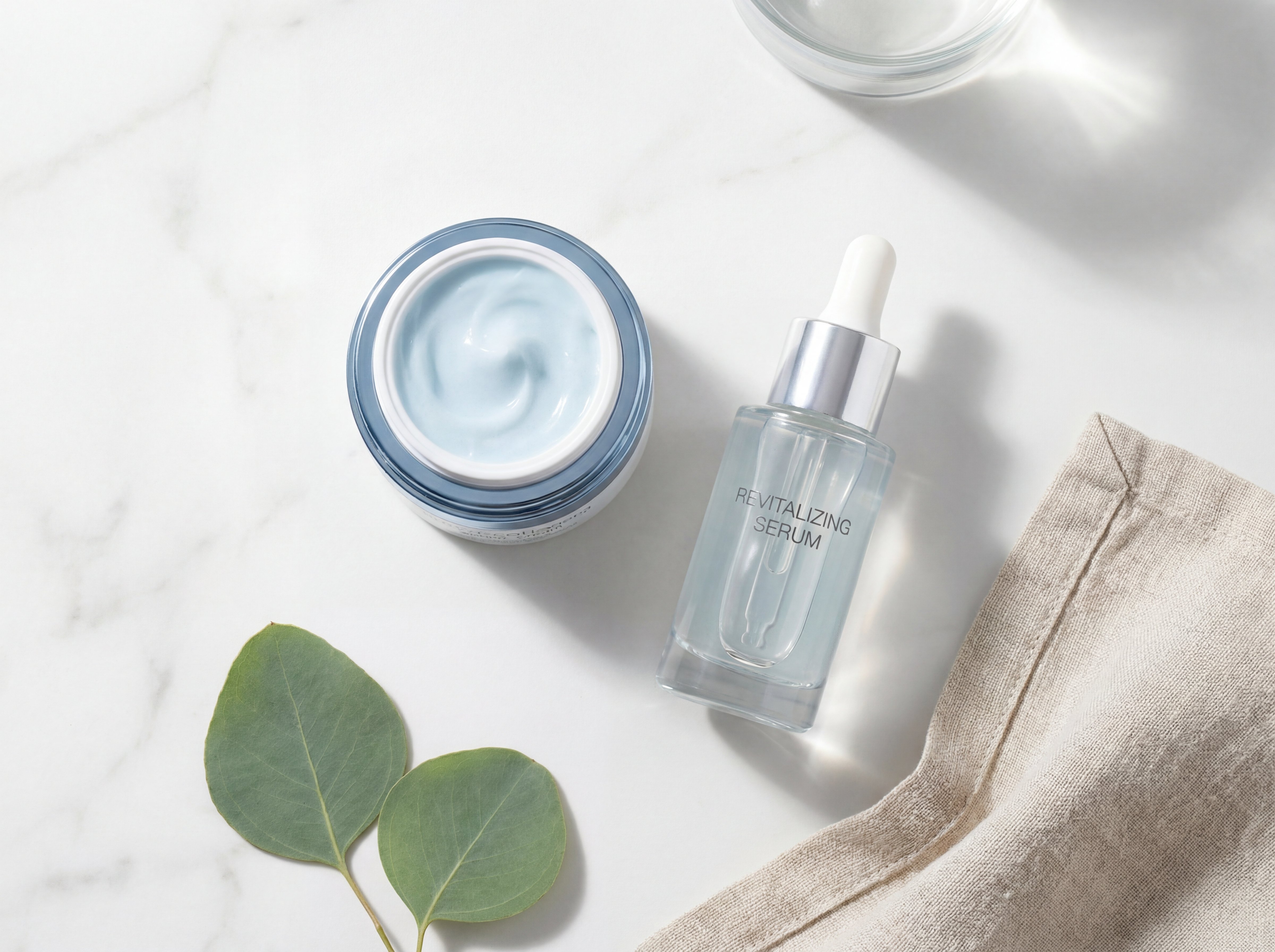 Minimal skincare flat lay showing serum and cream positioned together on white marble surface with natural lighting