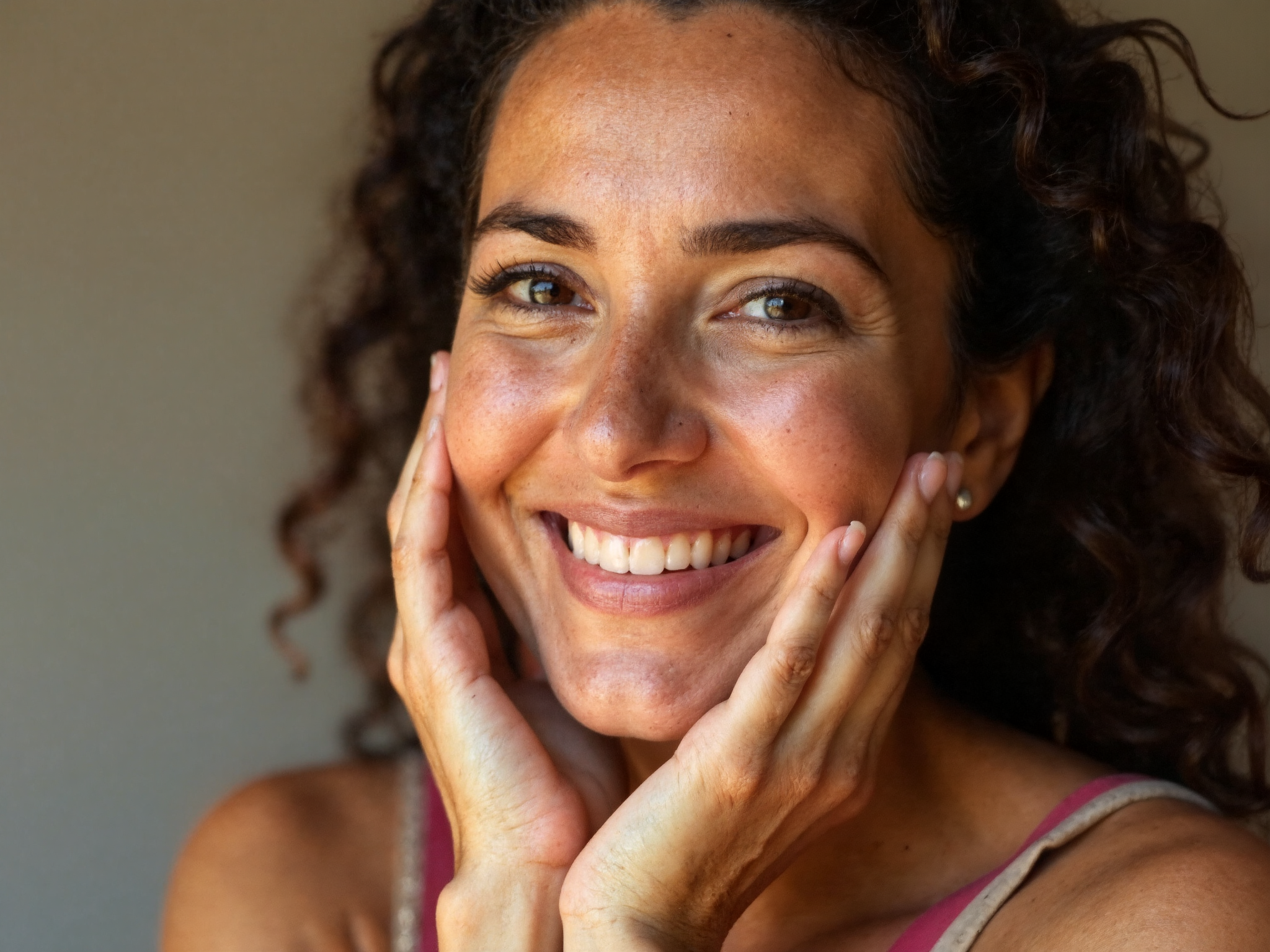 Woman in her forties touching her cheek with satisfied expression showing healthy restored skin barrier
