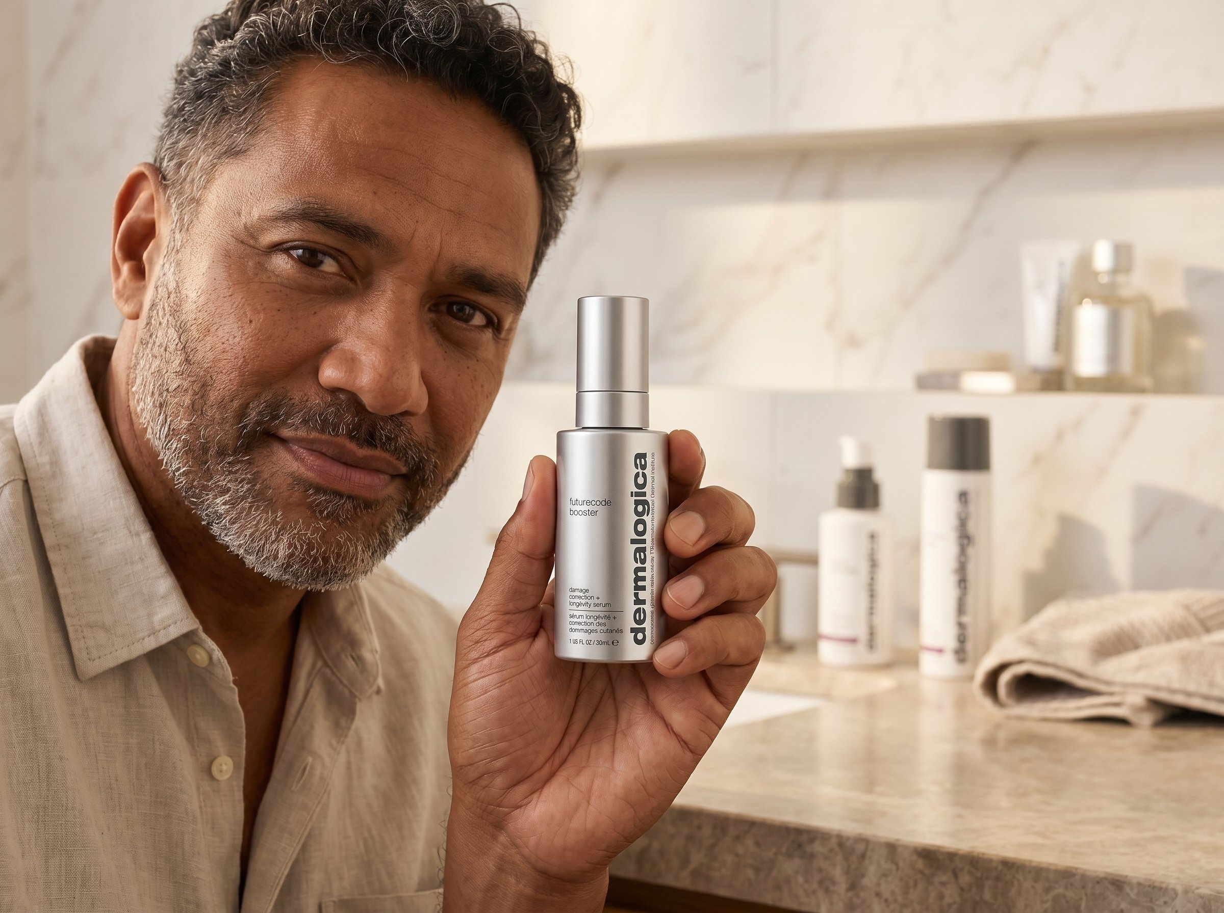 45-year-old Pacific Islander Australian man with brown skin holding a skincare serum dropper bottle in a warm bathroom setting