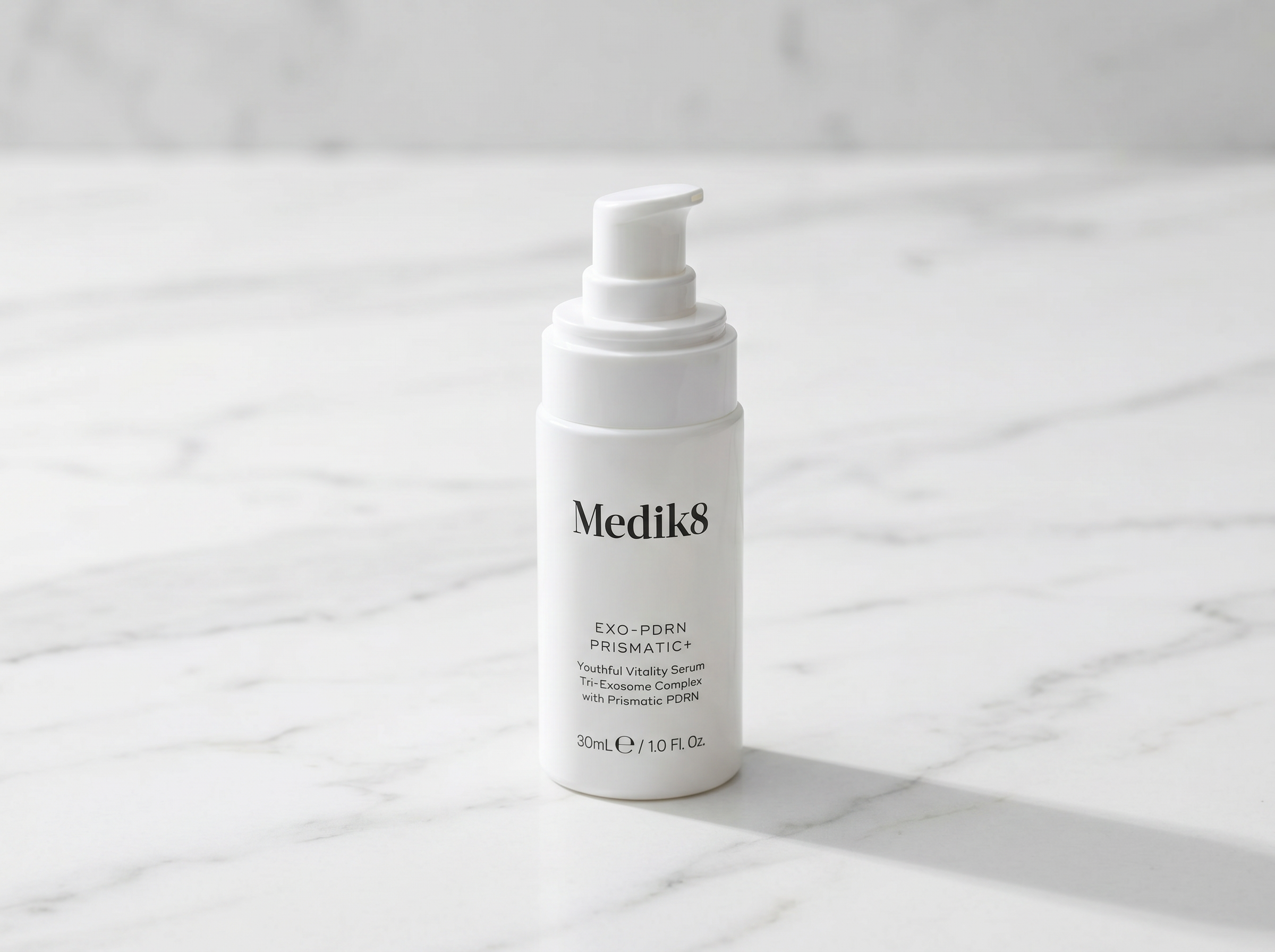 Exo-PDRN Prismatic+ serum bottle with dropper on white marble surface in soft natural light