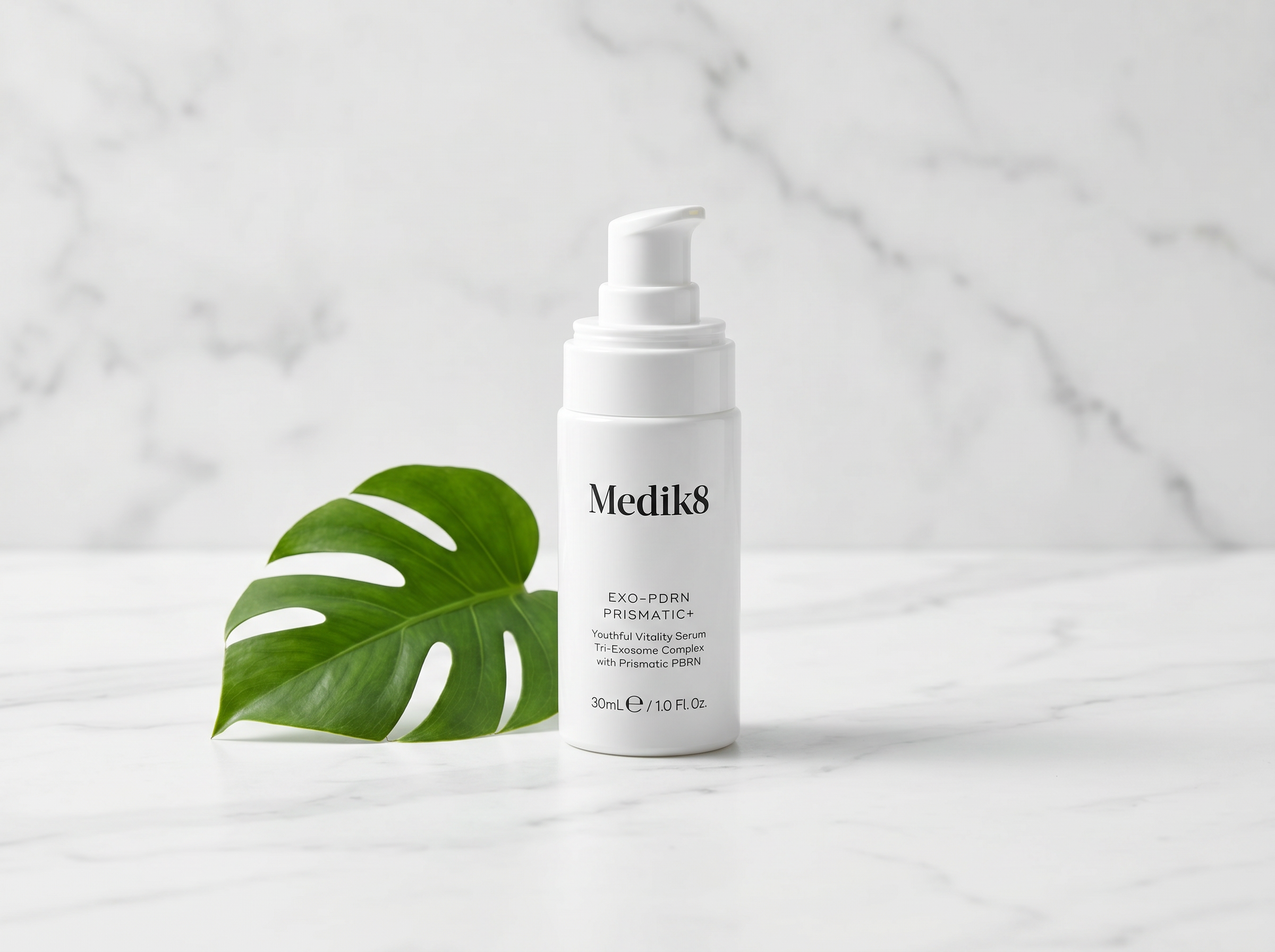 Exo-PDRN Prismatic+ serum bottle on white marble surface with soft studio lighting and minimal botanical styling
