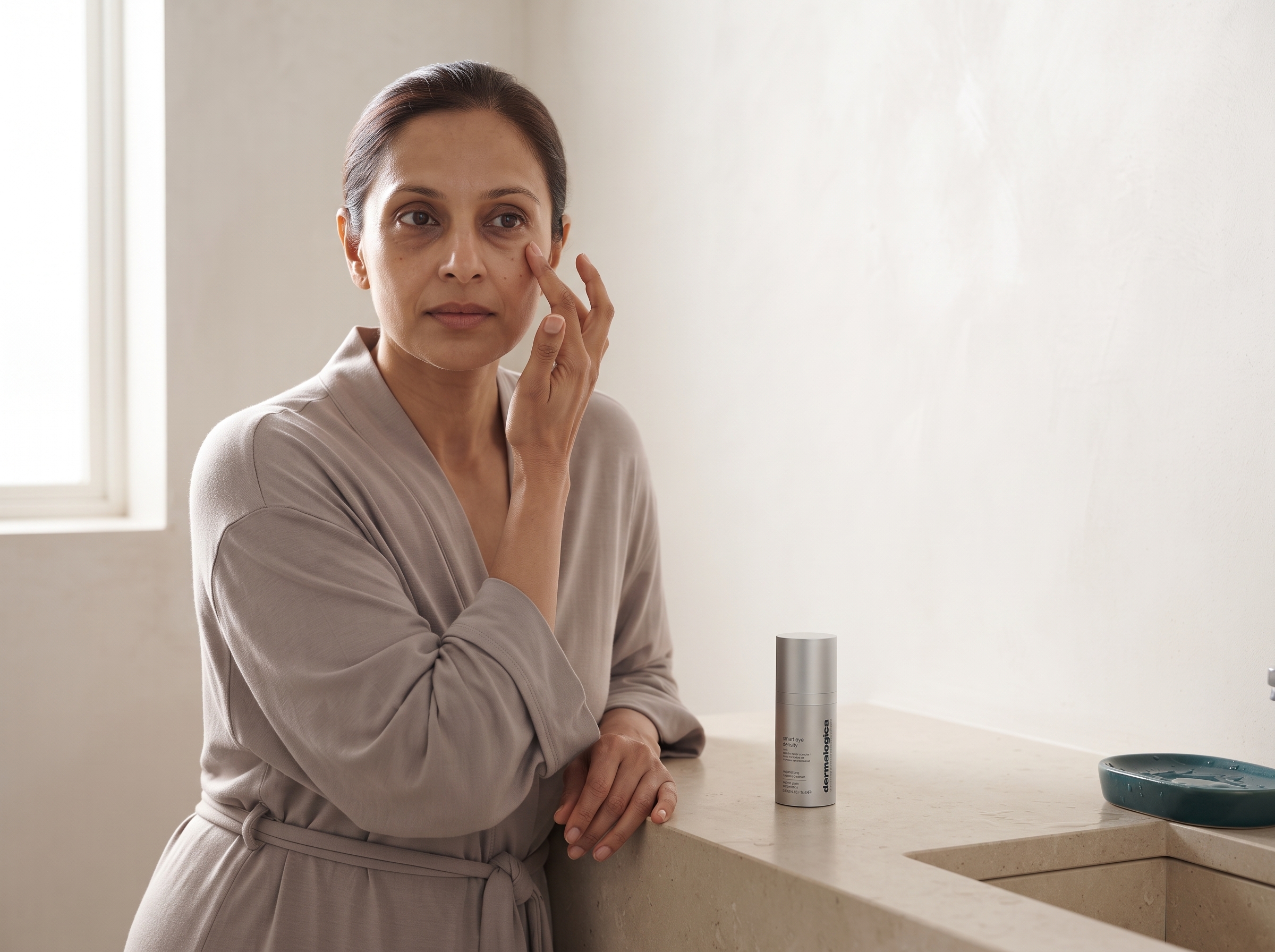 Woman applying eye serum with ring finger using a gentle tapping motion along the orbital bone